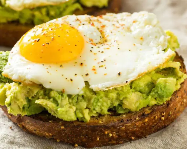 Tostada integral con aguacate machacado y huevo frito, un delicioso desayuno keto.