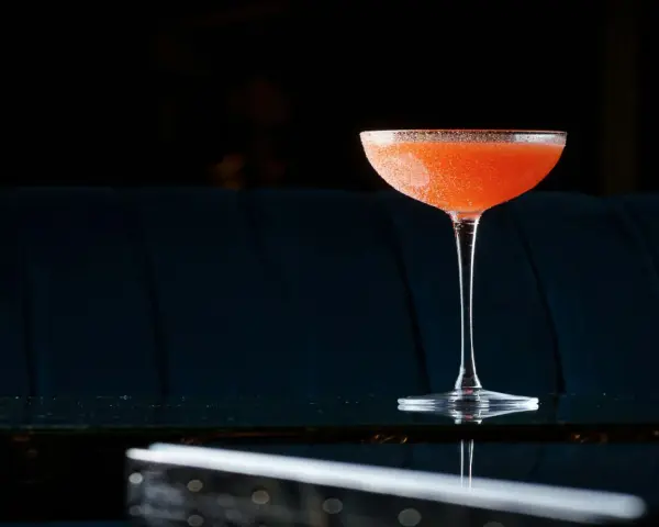 Orzeźwiający el presidente cocktail, z pomarańczowym odcieniem i cukrową obrączką, stoi na błyszczącym blacie.