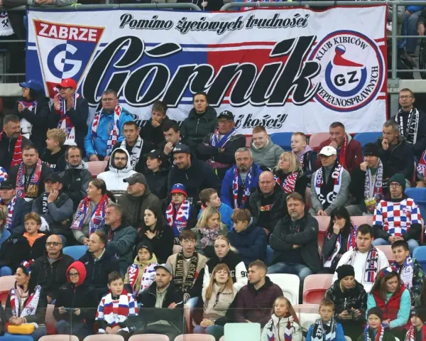Tłum kibiców Górnika Zabrze, w szalikach i barwach klubowych, wspiera drużynę.
