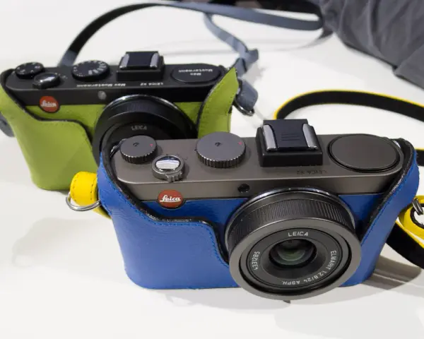 Dwie stylowe Leica X2 w kolorowych futerałach: jedna zielona, druga niebieska. Idealne do uchwycenia każdej chwili.