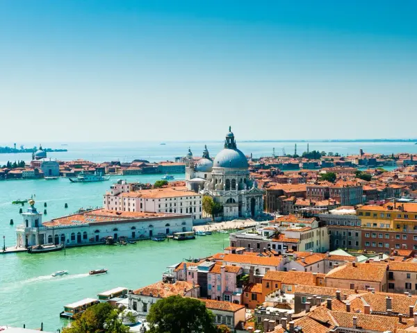 Venezia, con la sua Basilica di Santa Maria della Salute e i canali vibranti, offre infinite curiosità. Le case colorate e i tetti rossi si specchiano sull'acqua.