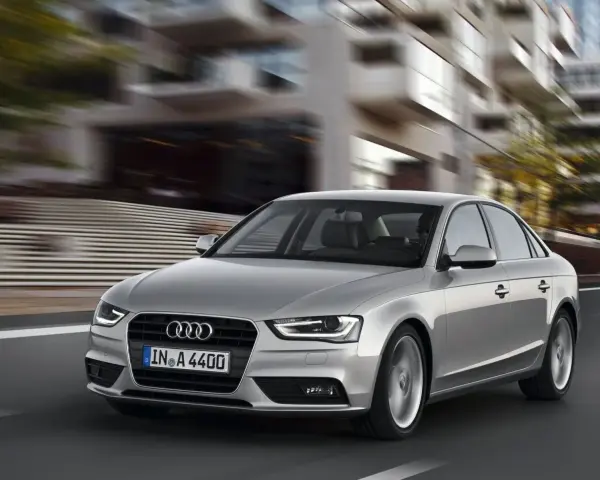 Srebrne Audi A4 B8 w ruchu miejskim, znane z typowych usterek, pędzi ulicą.