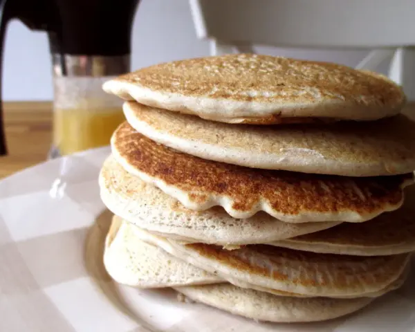 Pila di soffici pancake con farina di avena, dorati e invitanti, pronti per una colazione sana e gustosa.