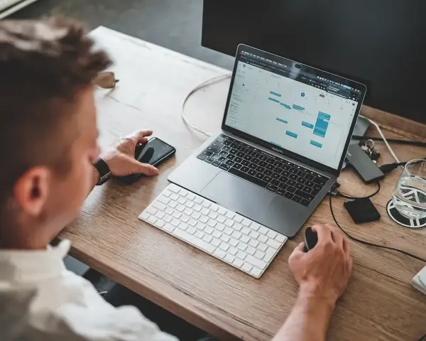 Mężczyzna pracuje przy laptopie, planując zadania. To idealne miejsce do nauki, by rozpocząć kurs spedytora i zdobyć nowe umiejętności.