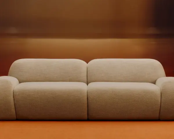 Divano beige bouclé, un materiale morbido e accogliente, con tavolini neri e lampade cromate.