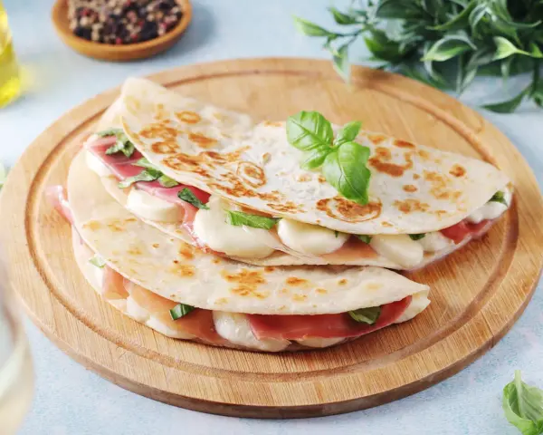 Piadina come farcirla: prosciutto, mozzarella filante e basilico fresco, un'idea gustosa e veloce.