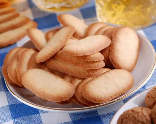 Un piatto pieno di croccanti lingue di gatto, perfette per accompagnare un tè o un caffè.