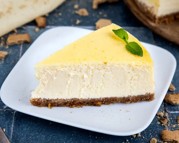 Ein cremiges Stück New York Cheesecake mit einem Keksboden, garniert mit Minze.