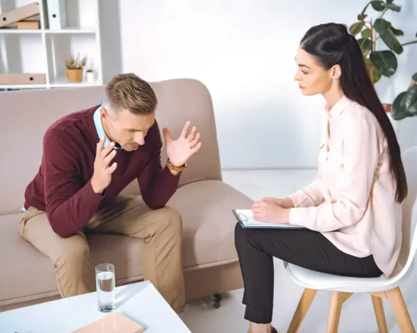 Mężczyzna rozmawia z psychologiem, siedząc na kanapie.
