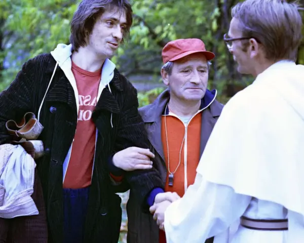 Czesław Nogacki w rozmowie z mężczyzną w białej szacie i z mężczyzną w czerwonej czapce.