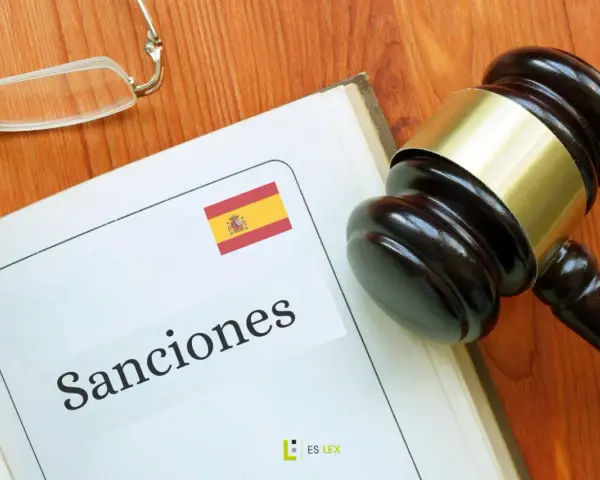 Martillo de juez sobre libro abierto con la palabra "Sanciones" y la bandera de España. Podría ser una multa hacienda.