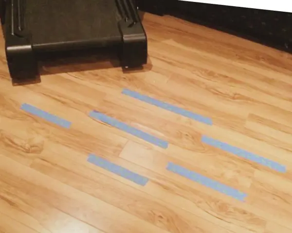 Marcando con cinta azul las tablas de tarima flotante levantadas por humedad para repararlas.