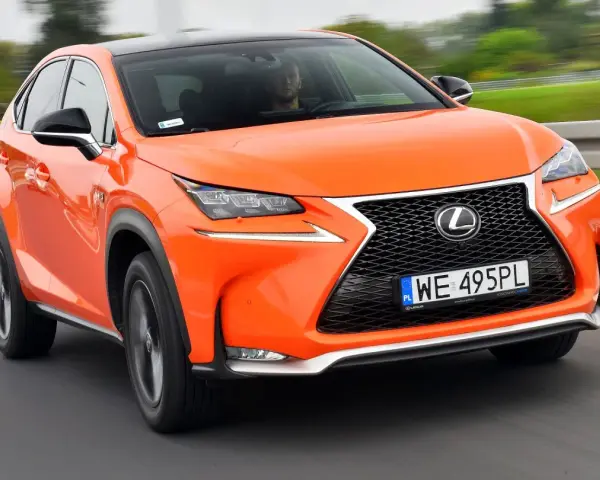 Pomarańczowy Lexus NX 300h w ruchu, z widocznym kierowcą.