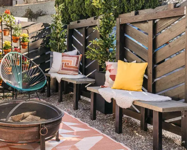 A cozy patio with a diy privacy screen, fire pit, and colorful chairs.