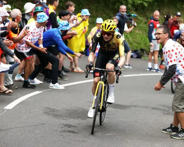 Jonas Vingegaard, with his impressive VO2 max, powers through a crowd of cheering fans in a cycling race.