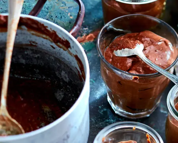Omas schokoladenpudding mit sahne, cremig und köstlich in Gläsern serviert. Ein Löffel wartet schon.