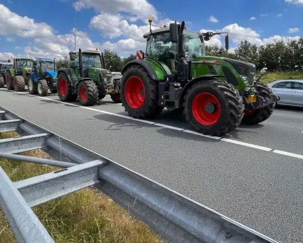 Una fila di trattori attraversa un'autostrada, un'immagine che ricorda che sulle autostrade e strade extraurbane principali è vietata la circolazione di macchine agricole.