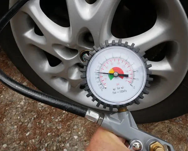 Misurazione della pressione delle gomme auto con manometro. La lancetta indica circa 2.5 bar.