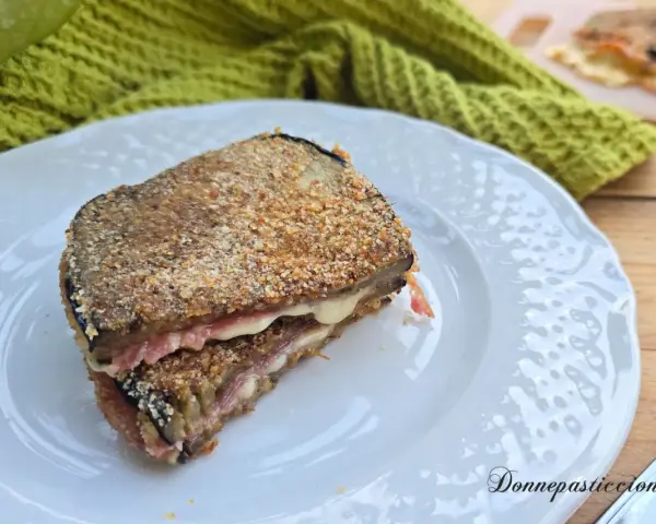 Un goloso cordon bleu di melanzane, impanato e fritto, con un cuore filante di formaggio e prosciutto.