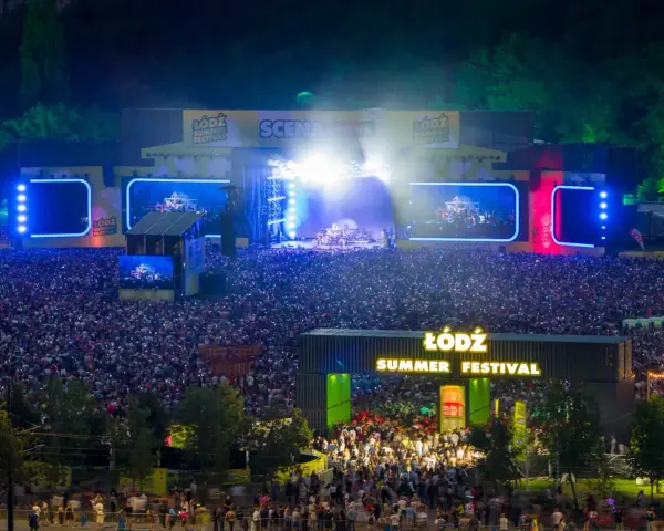 Tłum ludzi na koncercie podczas Łódź Summer Festival 2026. Na scenie gra zespół, a widzowie oświetlają teren telefonami.