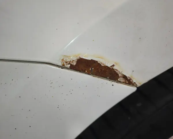 Rostfläckar på vit bil, dags att slipa rost innan det blir värre.