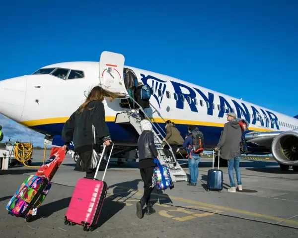 Ludzie z bagażami wsiadają do samolotu Ryanair. Może to być początek podróży lub sytuacja, gdy ktoś planuje **Ryanair zwrot biletu**.