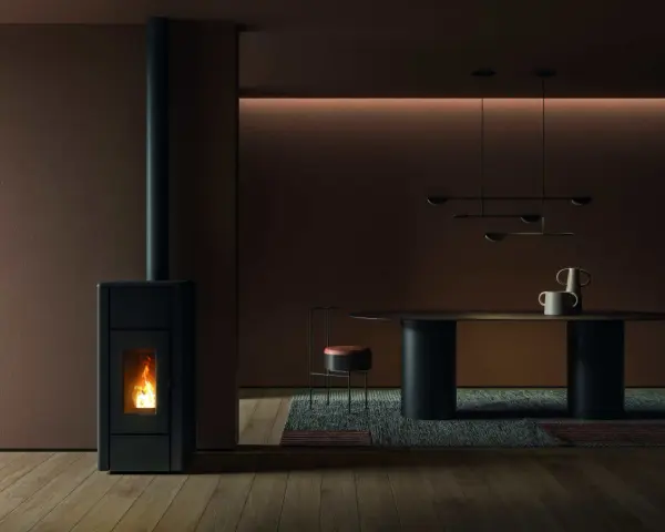 Un poêle à granulés dégage une douce chaleur, la flamme danse dans la chambre de combustion. La température ambiante est agréable, la fumée s'échappe par la cheminée.