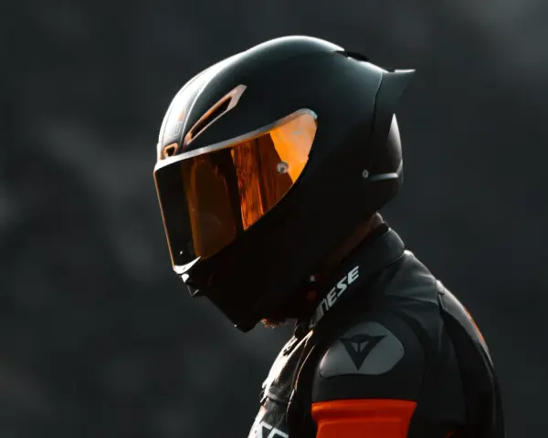 Casco nero lucido con visiera arancione riflettente, pronto per un giro in moto.