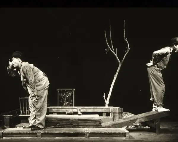 Dwóch mężczyzn w kapeluszach na scenie, w surrealistycznej scenografii. Scena z eugène ionesco sztuki, pełna absurdu i niepokoju.
