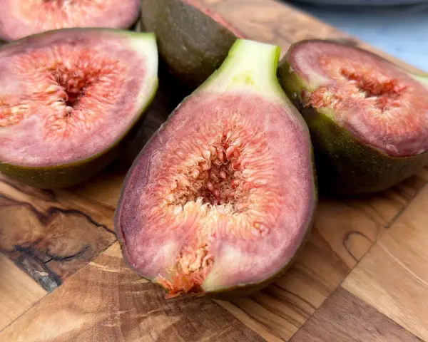 Saftige Feigen, aufgeschnitten auf einem Holzbrett. Die Schale ist nicht giftig, aber die Kerne sind essbar.