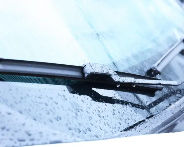 Scheibenwischer mit Wassertropfen. Die Scheibenwaschanlage funktioniert nicht. Woran kann das liegen? Vielleicht ist die Düse verstopft oder die Pumpe defekt.