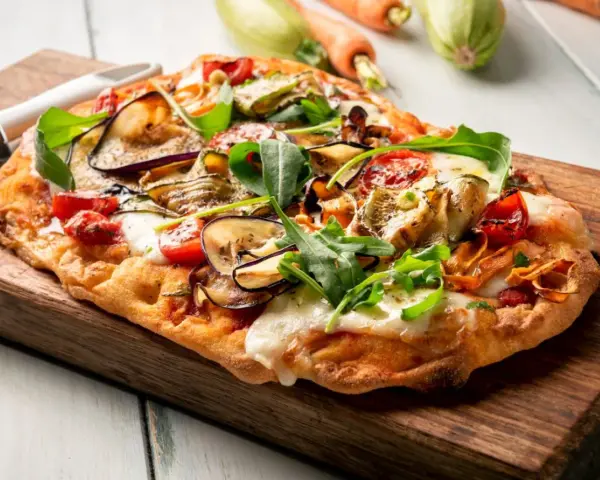 Chrupiący spód do pizzy z bakłażanem, cukinią i pomidorkami, posypany rukolą i mozzarellą.