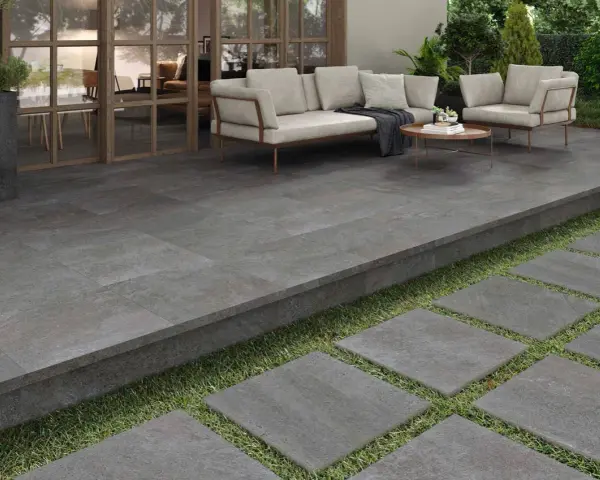 Terraza moderna con suelo de baldosas grises, ideal para saber como poner baldosas en suelo de tierra. Sofá y sillones invitan al descanso.