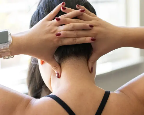 Hands demonstrate shiatsu self neck massage techniques, applying pressure to the base of the skull and sides of the neck.