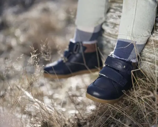 Granatowe, zimowe buty dziecięce na rzepy i sznurowadła, z futerkiem w środku. Wygodne i stylowe, idealne na jesienne i zimowe przygody. Różne marki butów oferują podobne modele.