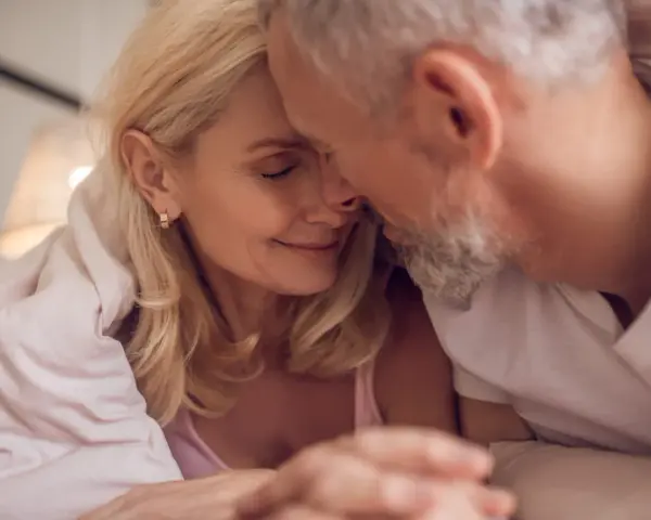 Couple âgé sous une couverture, évoquant la tendresse malgré la baisse de libido chez l'homme de 50 ans.