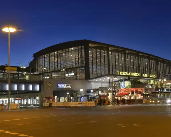 Der Bahnhof Zoo in Berlin bei Nacht. Die beleuchteten Terrassen am Zoo erstrahlen im Dunkeln.