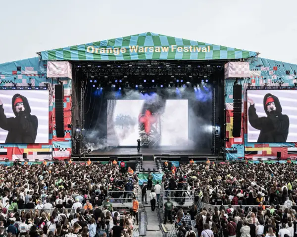 Tłum ludzi na Orange Warsaw Festival 2026, scena z artystą na ekranie i dymem.