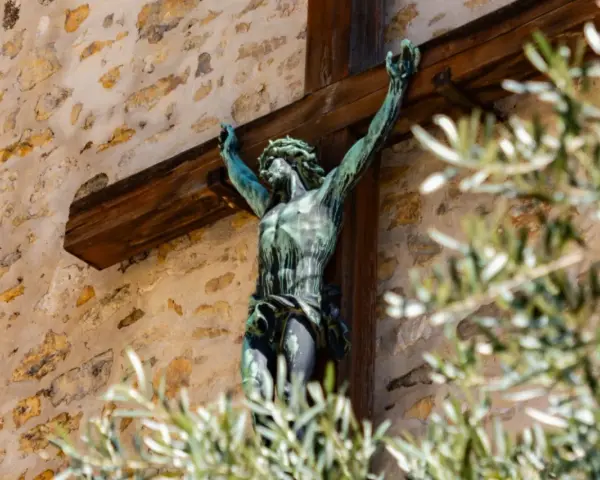 Brązowy Jezus na krzyżu, symbol chrześcijaństwa, na tle kamiennej ściany.