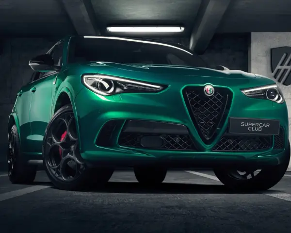 Zielony Alfa Romeo Stelvio Quadrifoglio z czarnymi felgami i czerwonymi zaciskami hamulcowymi, zaparkowany w garażu.