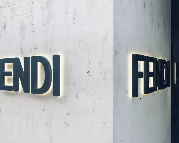Insegna luminosa Fendi su una parete di marmo. Il **Fendi significato** è lusso e artigianalità italiana.