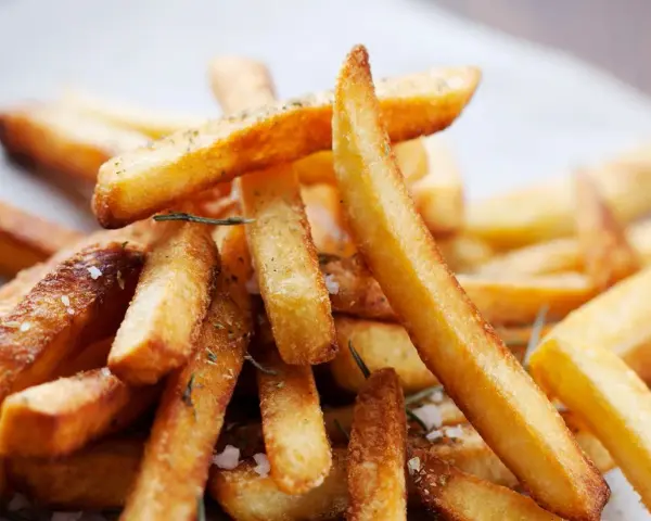 En hög med gyllene, krispiga pommes frites, strödda med örter och havssalt. Perfekt för en mysig hemmakväll.