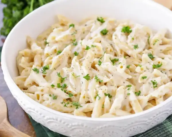 Penne w kremowym sosie śmietanowym, posypane świeżą natką pietruszki. Idealne na szybki obiad.