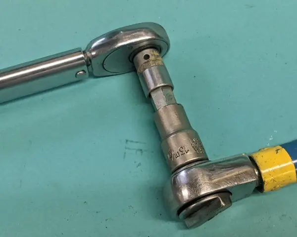 Två verktyg kopplade för att kalibrera momentnyckel. En momentnyckel i metall och en blå/gul skruvdragare med hylsa.