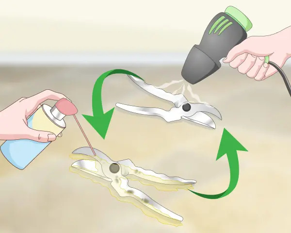 Hands spray lubricant onto pruning shears to remove rust. A heat gun is then used to dry them.