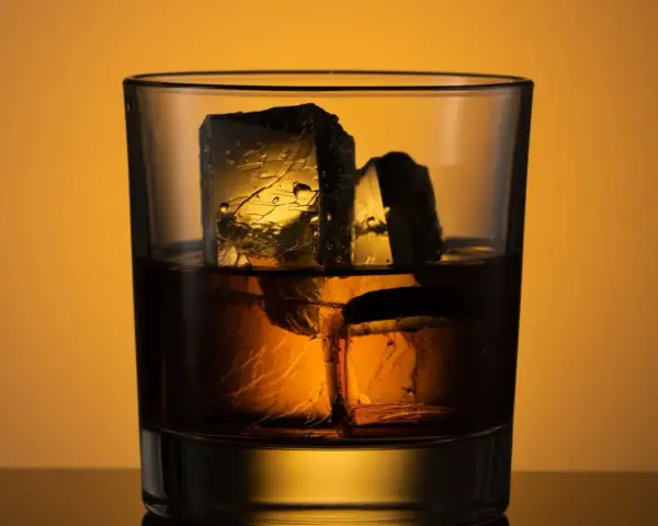 Ein Glas mit **whiskey neat**, zwei große Eiswürfel darin, beleuchtet von warmem Licht.