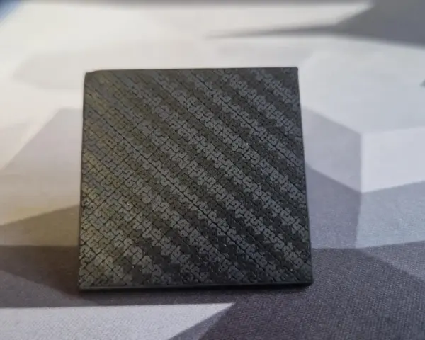 A small cube with a textured surface, showcasing the intricate pattern achieved through carbon fiber 3D printing.