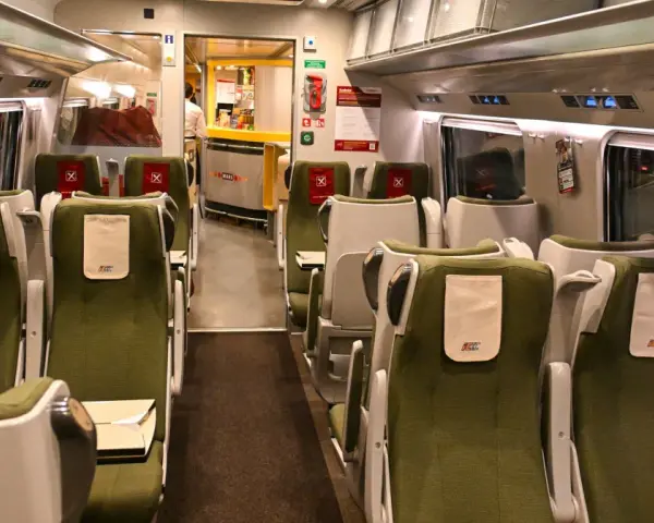 Wnętrze wagonu PKP Intercity IC 4520 Hutnik. Rozkład miejsc w zielonych fotelach, z widocznym barem Wars.
