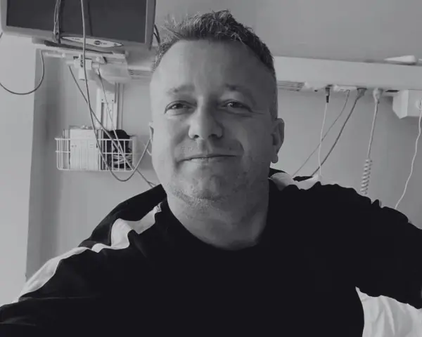 Uśmiechnięty mężczyzna w szpitalnym łóżku, słuchający dj hazel utwory.