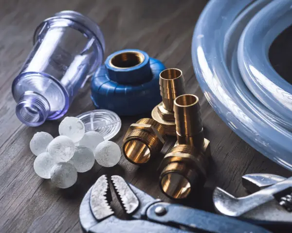 Componenti per caldaia: filtro, raccordi, tubo e palline per addolcitore. Utili per capire ogni quanto cambiare sali caldaia.